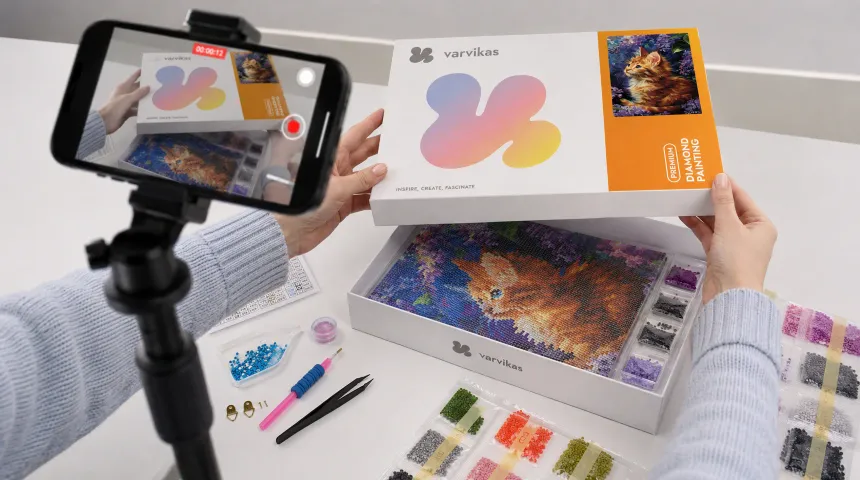 Loyalty program hobby reward promotion showing a crafter recording a diamond painting unboxing video on a smartphone, with colorful drills, tools, and creative kit components displayed for earning a 15% bonus through customer video reviews.
